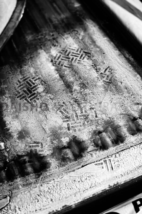 画像: この画像は、車の汚れた表面に付いたタイヤ跡です。白黒の色調が施され、滑らかで膜状の汚れが特徴的です。 キーワード: 車の